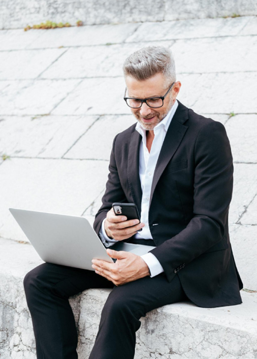 A business professional using a laptop and phone to access T Bank's cash management services.